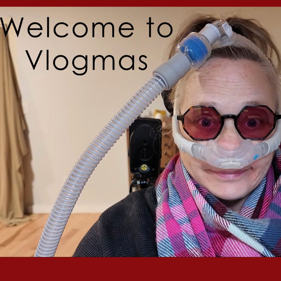 Portrait photograph of Connie wearing a black sweatshirt and pink scarf with the words typed welcome to vlogmas