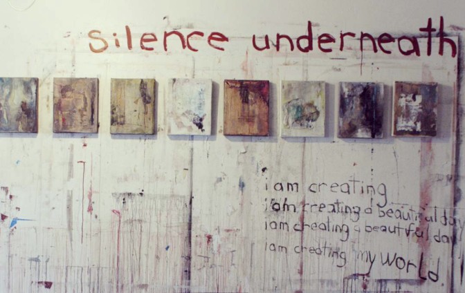 image of a dirty white wall from paint with small painting hung across the wall near top of image. a little dark grey floor showing at the bottom of the image